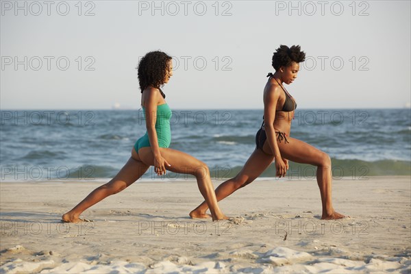 Women practicing yoga on beach