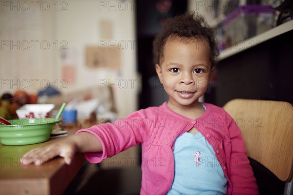 Mixed race baby girl sitting at table