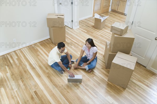 Asian couple looking at laptop in new house