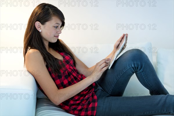 Asian girl using digital tablet on sofa