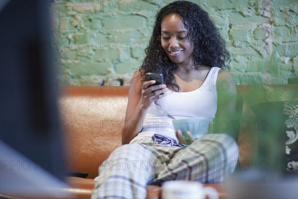 Mixed race woman having breakfast and using cell phone