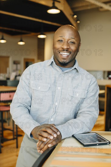 Black waiter using digital tablet in cafe