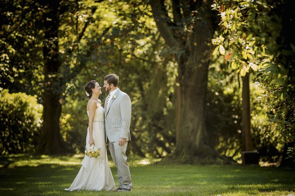 Caucasian bride and groom walking in grass