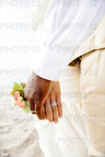 Newlywed couple holding hands on beach