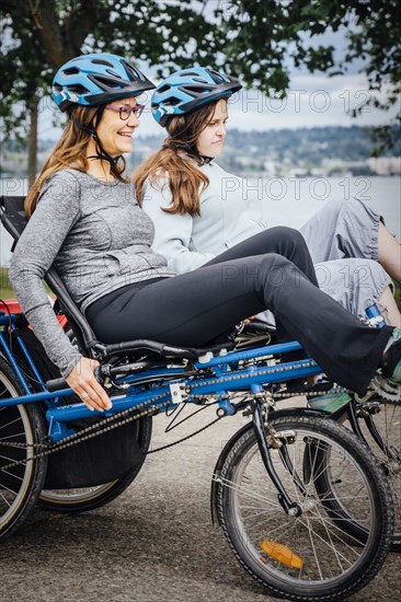 Caucasian mother and daughter riding tandem bicycle