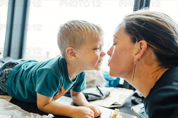 Mother kissing son laying on table