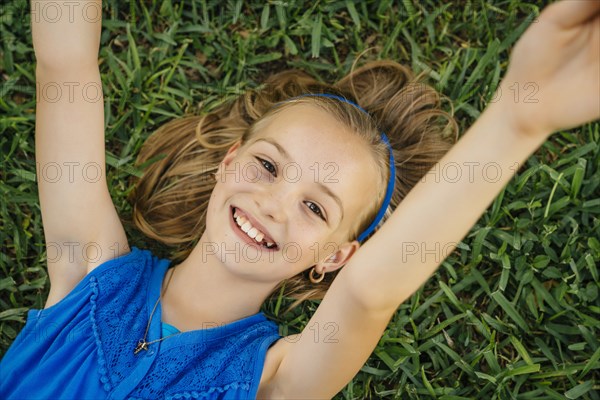 Close up portrait of smiling Caucasian girl laying on grass