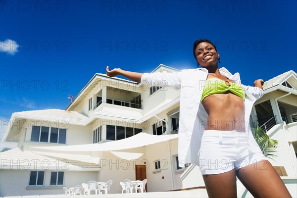 African woman with arms outstretched poolside