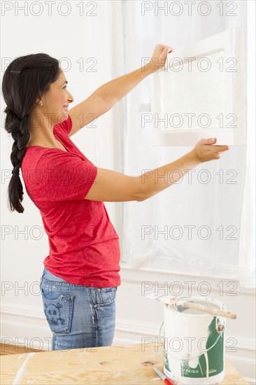 Mixed race woman installing window pane