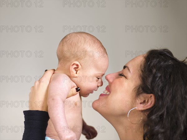 Mother holding newborn baby face to face