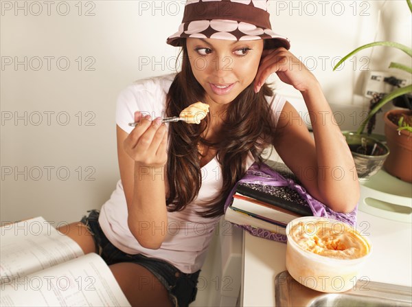 Hispanic woman eating ice cream and studying