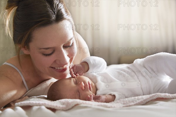 Mother admiring newborn baby on bed