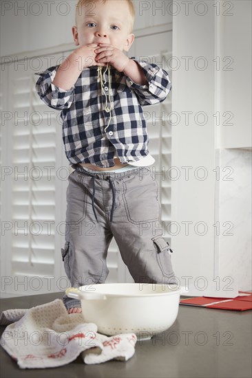 Caucasian boy standing on table playing with food