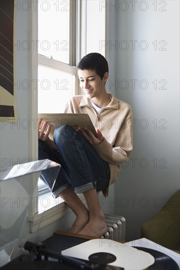 Mixed race teenage boy listening to records