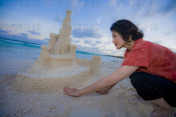 Japanese woman building elaborate sand castle at beach
