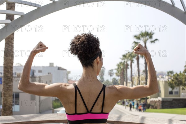 Mixed Race woman flexing arms