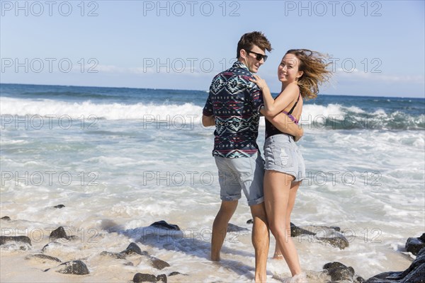Smiling couple hugging on windy beach