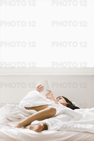 Caucasian woman reading book in bed