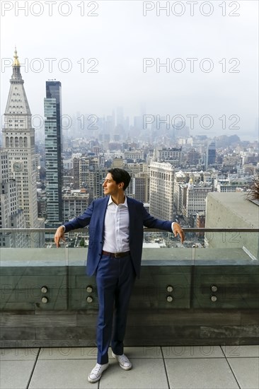 Pensive Caucasian businessman leaning on urban rooftop