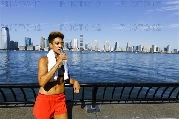 Mixed race woman drinking water from bottle at waterfront