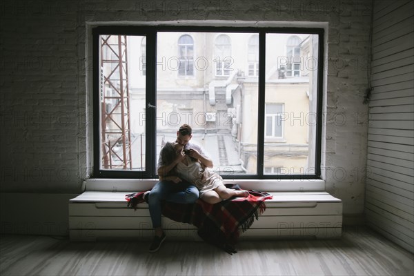 Caucasian couple kissing on bench near window