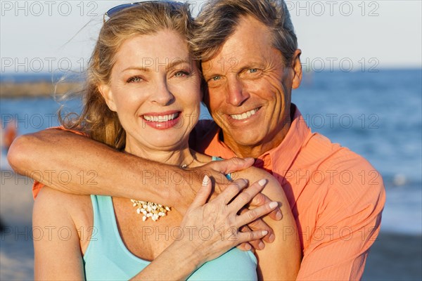 Older Caucasian couple hugging on beach