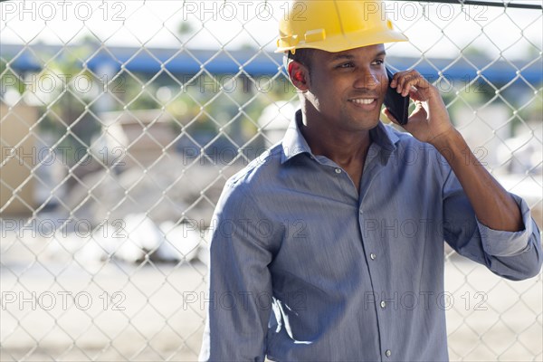 Black architect in hard hat talking on cell phone