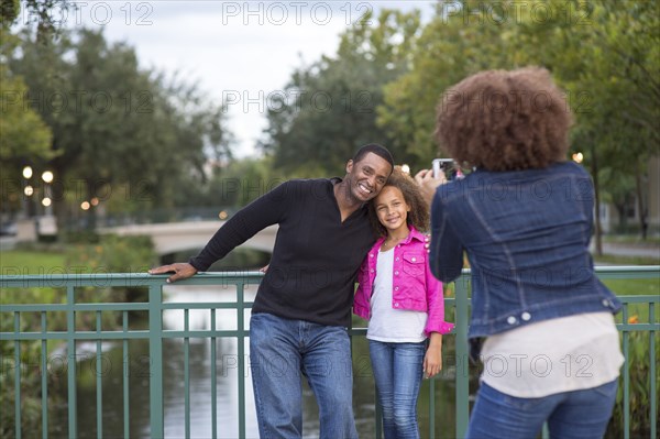 Mother photographing family on bridge