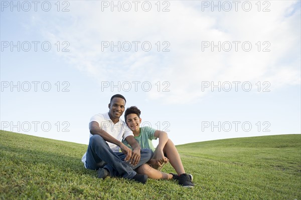 Father and son sitting in grass