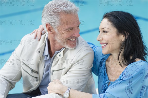 Caucasian couple hugging poolside