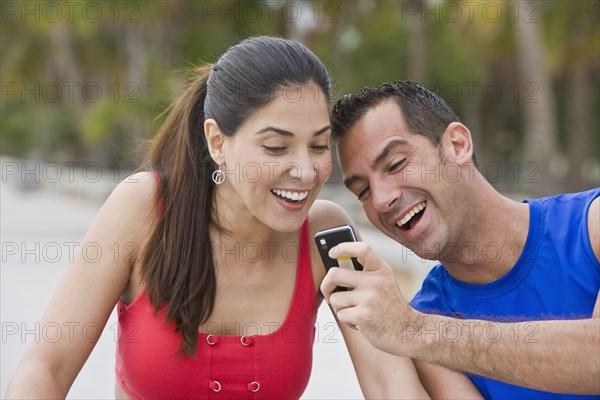 Hispanic man showing girlfriend cell phone