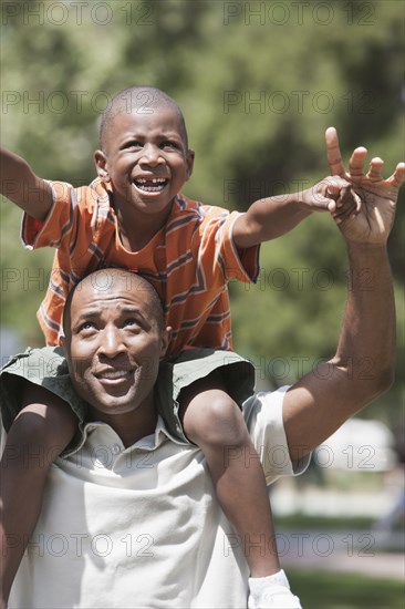 Father carrying son on shoulders in park