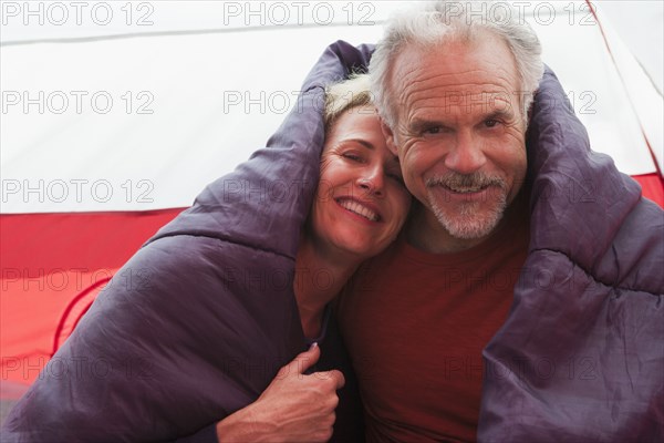 Senior Caucasian couple in sleeping bag in tent