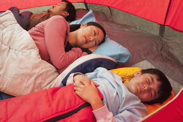 Asian family sleeping in tent