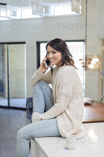 Caucasian woman sitting on table talking on cell phone