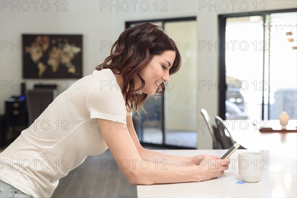 Caucasian woman leaning on table texting on cell phone