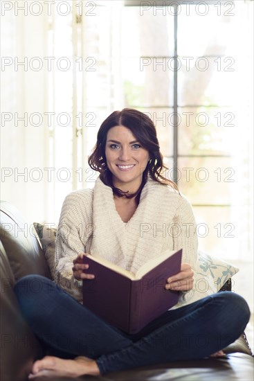 Caucasian woman sitting on sofa reading book