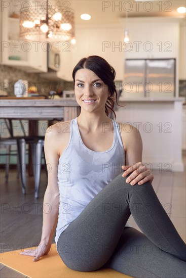 Smiling Caucasian woman sitting on exercise mat