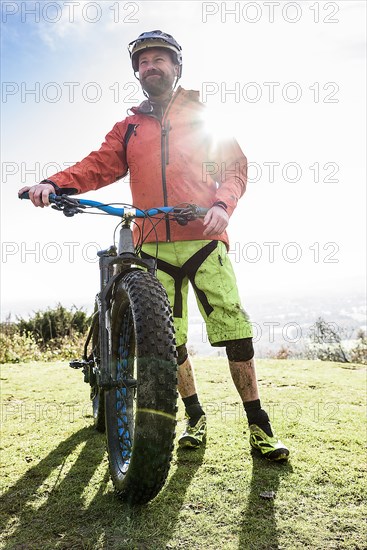 Portrait of smiling Caucasian man splattered in mud holding bicycle