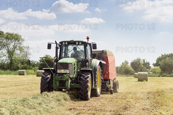 Caucasian man driving tractor baling hay