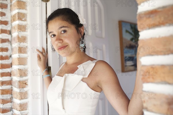 Hispanic bride standing in doorway