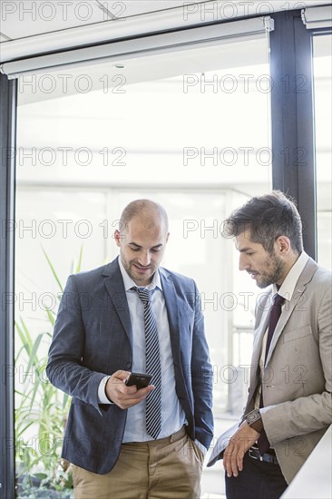 Caucasian businessmen using cell phone in office lobby