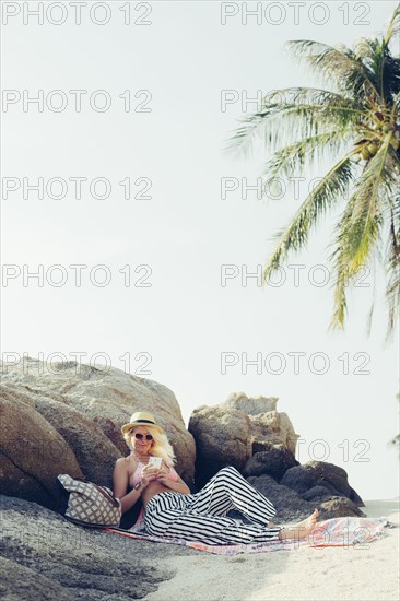 Caucasian woman using cell phone on beach