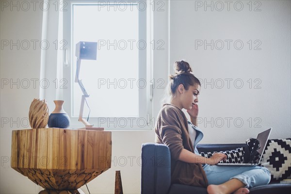 Caucasian woman using laptop on sofa