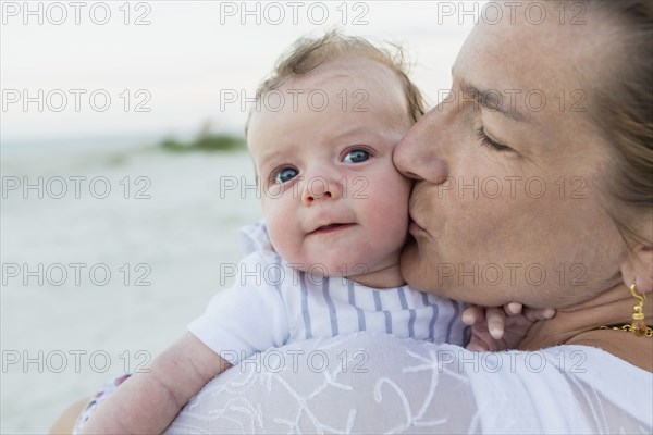 Mother kissing baby on beach