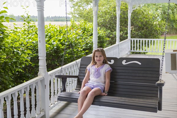 Caucasian girl relaxing in swing on porch