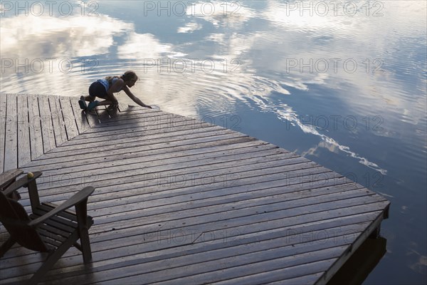Caucasian girl on wooden deck making ripples in lake
