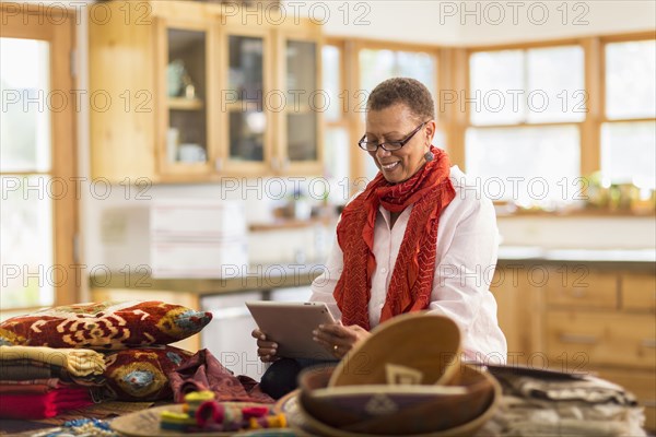Older mixed race woman using digital tablet in home office