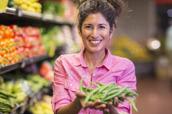 Hispanic woman holding vegetables at grocery store