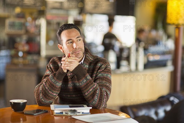 Hispanic businessman using digital tablet in coffee shop